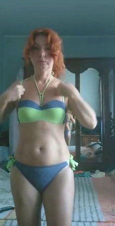 Рыжеволосая зрелая женщина примеряет купальник